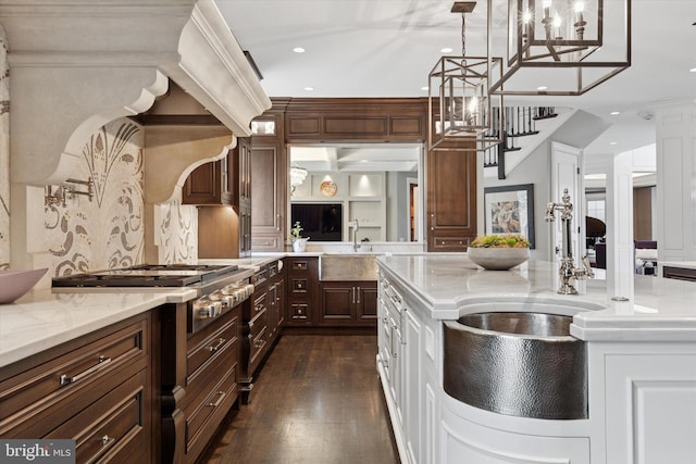 kitchen with stainless steel gas cooktop, recessed lighting, dark wood-type flooring, light stone counters, and a sink