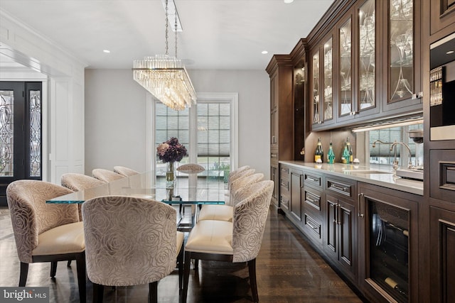 dining space with an inviting chandelier, recessed lighting, dark wood-type flooring, and beverage cooler