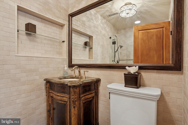 bathroom featuring visible vents, tile walls, walk in shower, vanity, and toilet