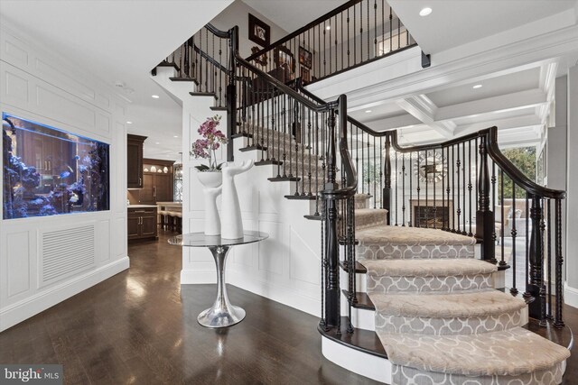 staircase with wood finished floors, recessed lighting, coffered ceiling, and a decorative wall