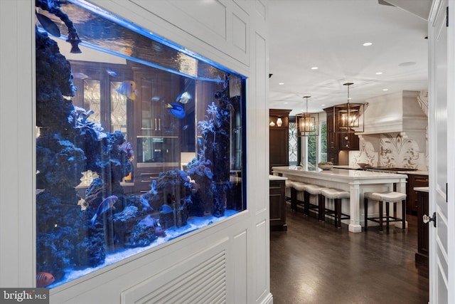 bar with pendant lighting, premium range hood, recessed lighting, dark wood finished floors, and a notable chandelier