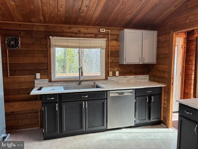 kitchen featuring a sink, stainless steel dishwasher, and wooden walls