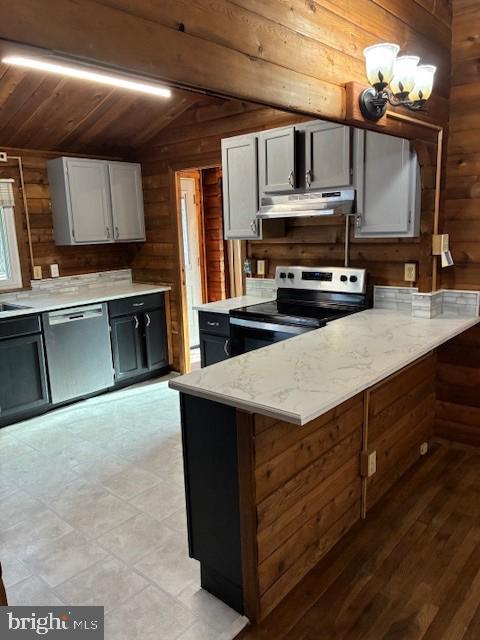 kitchen with wooden walls, a peninsula, stainless steel appliances, vaulted ceiling, and under cabinet range hood