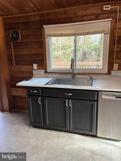 kitchen with a sink, wood ceiling, dark cabinetry, light countertops, and dishwasher