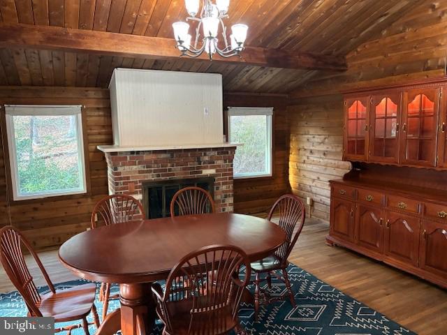 dining room with lofted ceiling with beams, wood ceiling, light wood-style floors, wood walls, and a chandelier