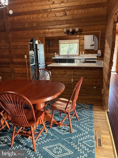 dining space with visible vents, arched walkways, wood finished floors, and wood walls