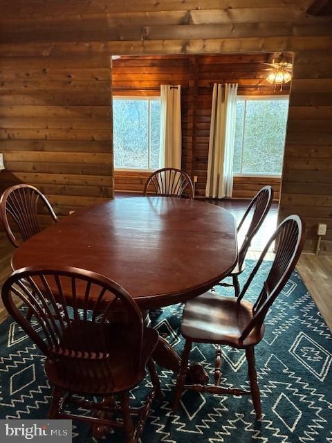 dining space with wooden walls, wood finished floors, and a wealth of natural light