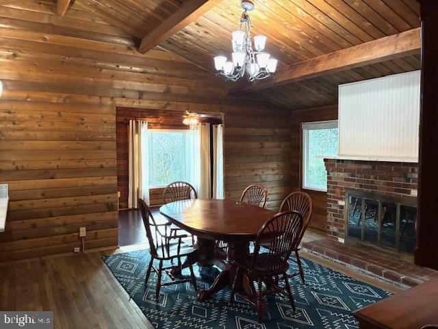 dining space with wooden walls, a healthy amount of sunlight, and vaulted ceiling with beams