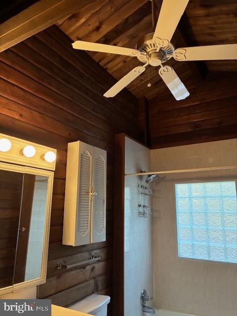 full bath with a ceiling fan, wood walls, washtub / shower combination, wooden ceiling, and vaulted ceiling