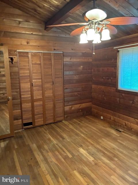 unfurnished bedroom featuring wood walls, wooden ceiling, a ceiling fan, and hardwood / wood-style flooring