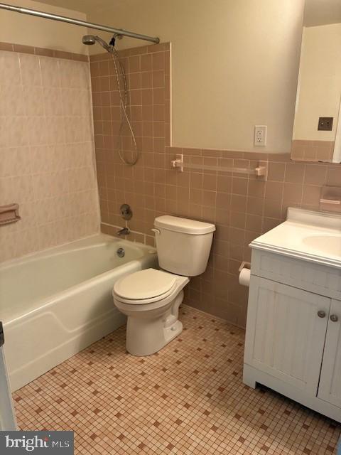 full bathroom featuring vanity,  shower combination, tile patterned flooring, tile walls, and toilet