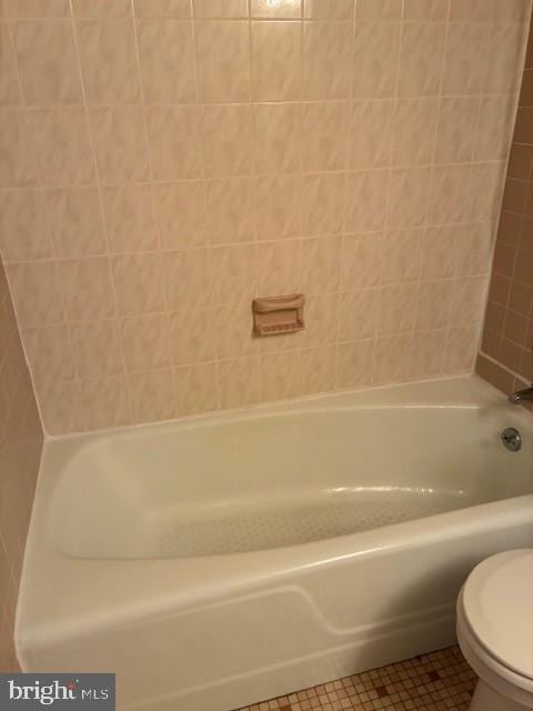 full bath with tile patterned floors, toilet, and a washtub