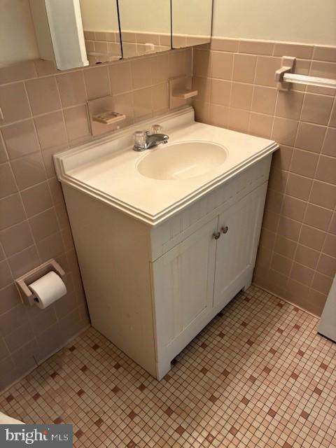 bathroom with vanity, tile walls, tile patterned flooring, and wainscoting