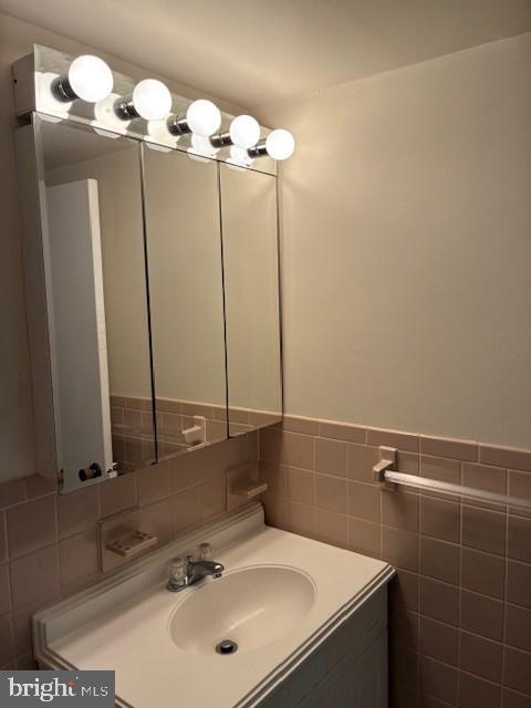 bathroom with a wainscoted wall, tile walls, and vanity