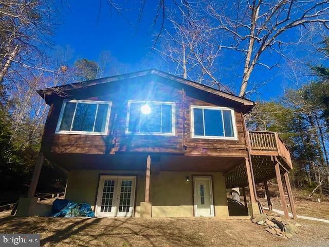 rear view of property featuring french doors, a wooden deck, and stucco siding