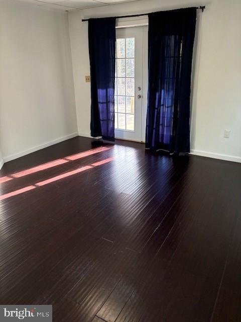spare room with baseboards and wood finished floors