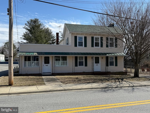 view of front of house featuring a chimney, a porch, and metal roof