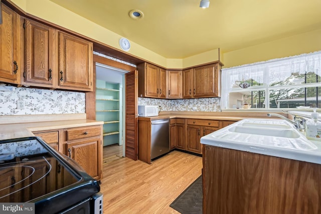 kitchen with brown cabinets, dishwasher, light wood-type flooring, white microwave, and black range with electric stovetop