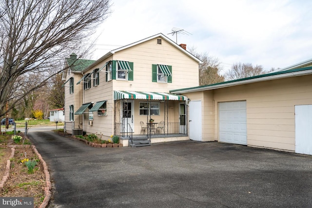 traditional-style house featuring central AC, driveway, a chimney, and an attached garage