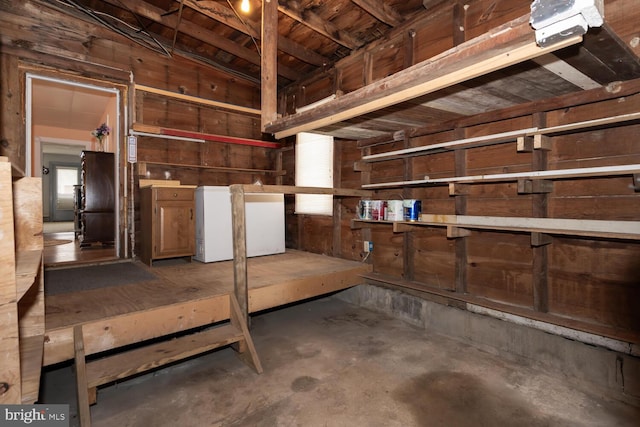 basement with wooden walls and refrigerator