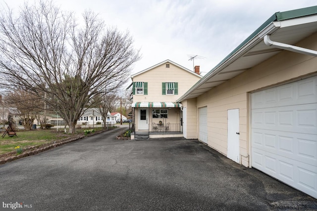 view of front of property with a garage, aphalt driveway, and a chimney