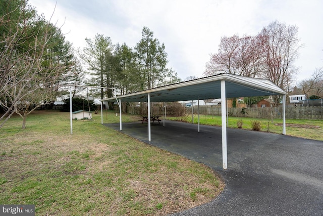 view of parking with fence, driveway, and a carport