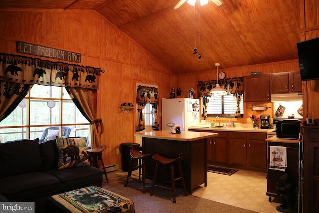 kitchen featuring wooden walls, wooden ceiling, light countertops, and freestanding refrigerator