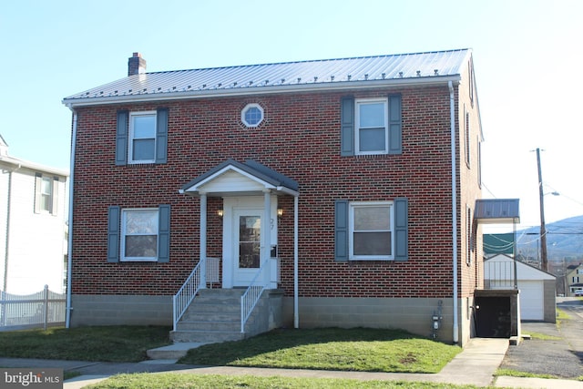 view of front of property featuring brick siding, a chimney, and metal roof