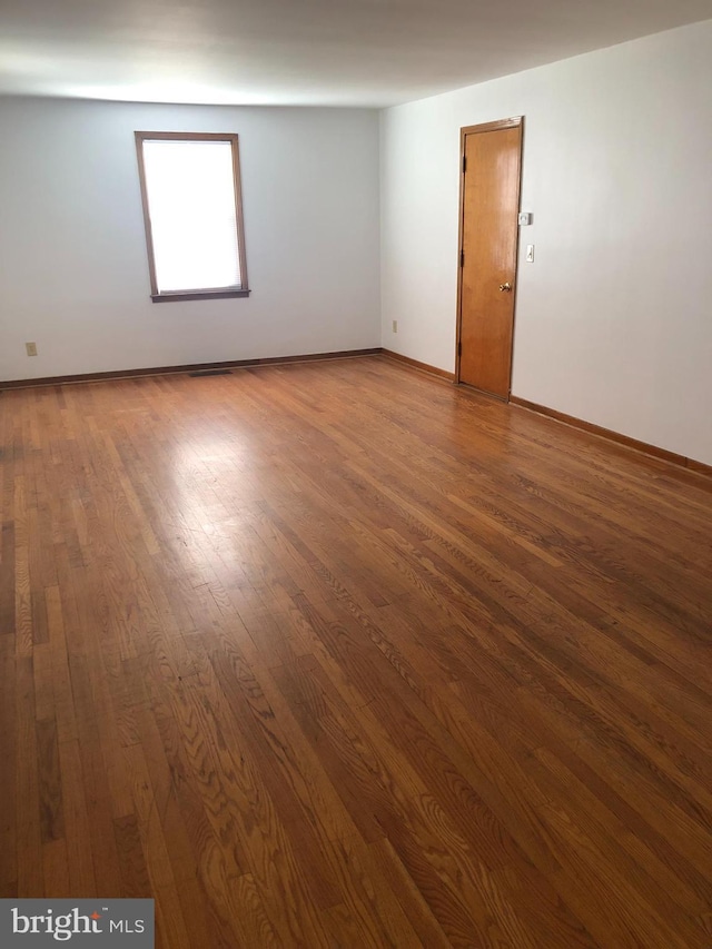 unfurnished room with baseboards and wood finished floors