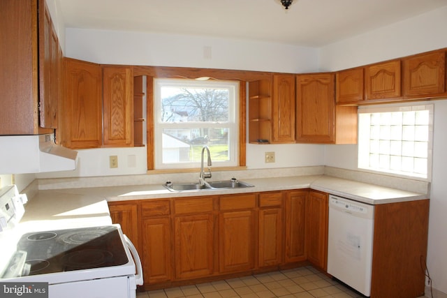 kitchen with white appliances, plenty of natural light, range hood, and a sink