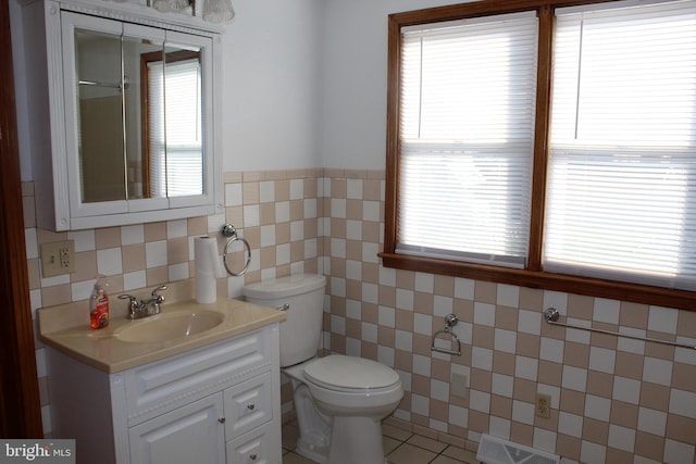 bathroom with visible vents, a wainscoted wall, toilet, tile walls, and vanity
