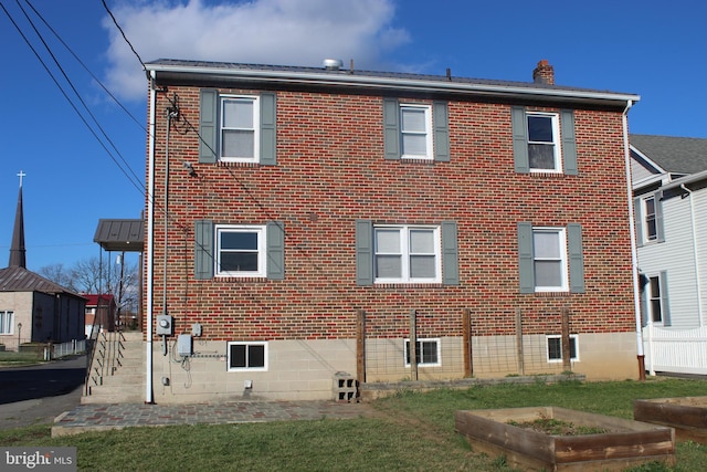 back of property with a yard, fence, brick siding, and a chimney