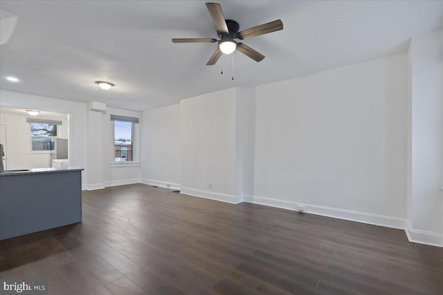 unfurnished living room with dark wood finished floors, baseboards, and ceiling fan
