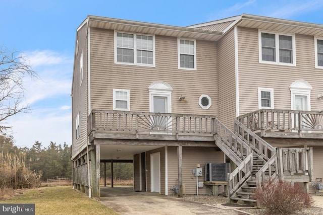 back of house featuring a wooden deck, stairs, cooling unit, a carport, and driveway