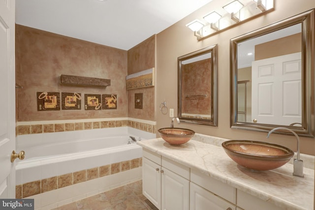 full bathroom featuring double vanity, tiled tub, a sink, and tile patterned floors