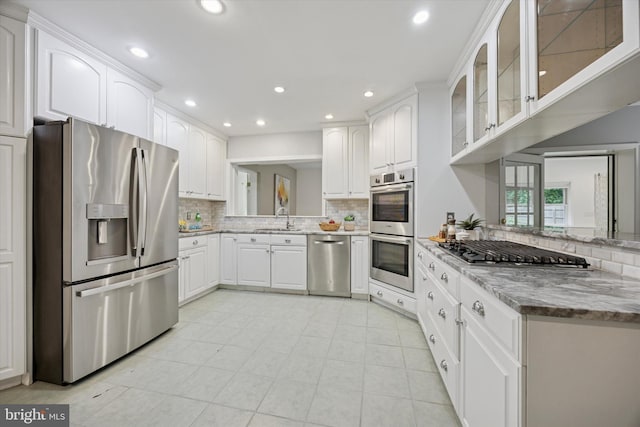 1220 Wendover Rd, Bryn Mawr, PA 19010 - kitchen featuring glass insert cabinets, a sink, backsplash, stainless steel appliances, and white cabinets
