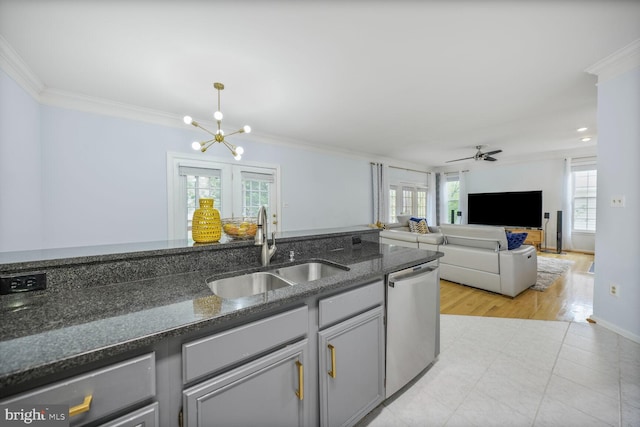 kitchen featuring stainless steel dishwasher, a sink, ceiling fan with notable chandelier, dark stone countertops, and ornamental molding