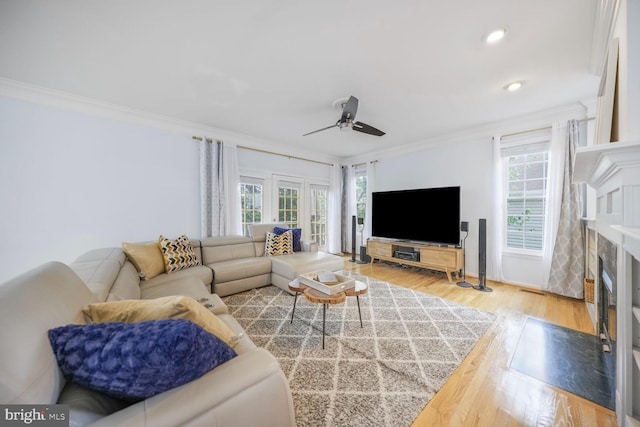 living room featuring a ceiling fan, a fireplace, wood finished floors, ornamental molding, and recessed lighting