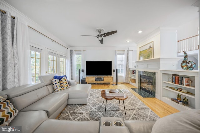 living area featuring crown molding, a fireplace, ceiling fan, recessed lighting, and light wood finished floors