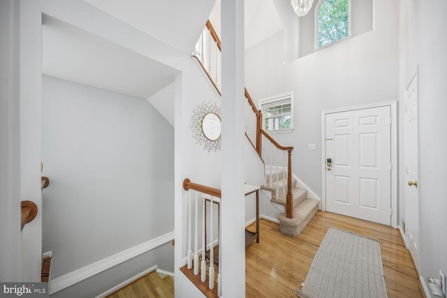 foyer entrance with plenty of natural light, stairs, wood finished floors, and a towering ceiling