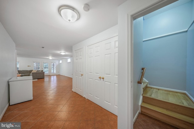 hall with baseboards, tile patterned floors, and stairway