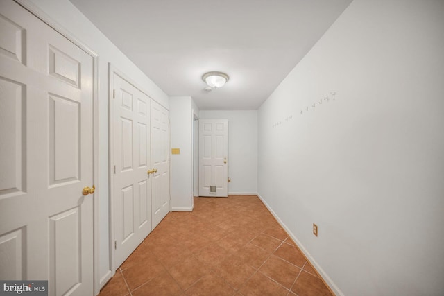 hallway featuring baseboards and tile patterned floors