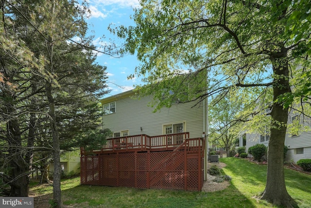 back of house with a lawn, a wooden deck, and cooling unit