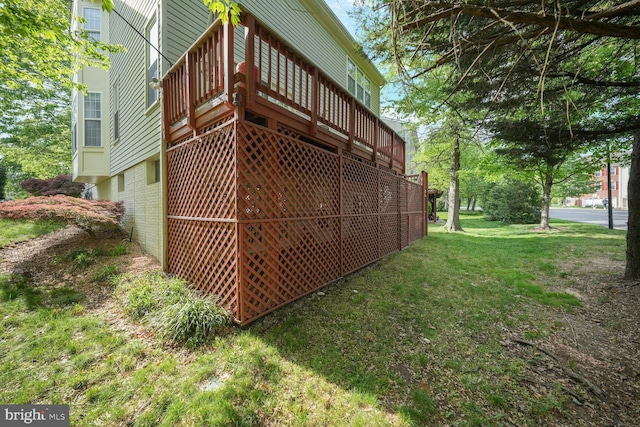 exterior space with a yard, a deck, and brick siding