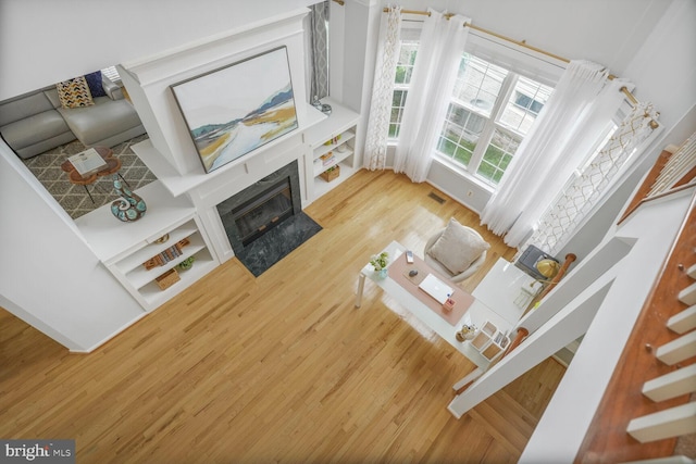 living room featuring a fireplace, stairs, wood finished floors, and visible vents