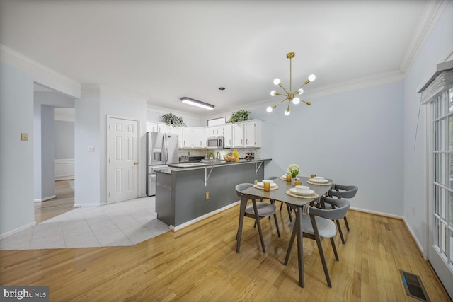 dining area featuring visible vents, ornamental molding, light wood finished floors, and a notable chandelier