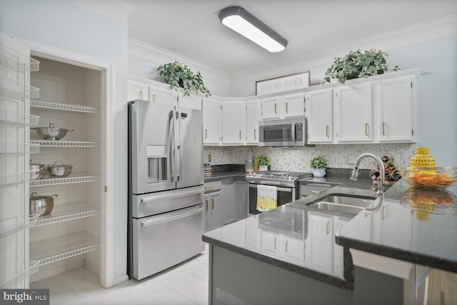 kitchen with crown molding, appliances with stainless steel finishes, a sink, light tile patterned floors, and dark stone countertops