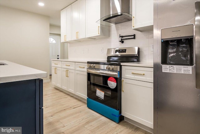 kitchen with light wood-style flooring, white cabinetry, wall chimney range hood, and stainless steel appliances