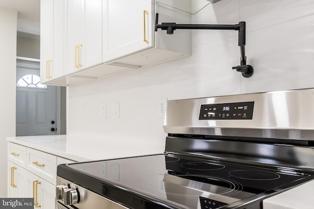 kitchen with light countertops, white cabinets, and stainless steel range with electric cooktop