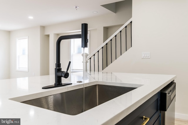 interior space with stainless steel dishwasher, a sink, dark cabinets, and recessed lighting